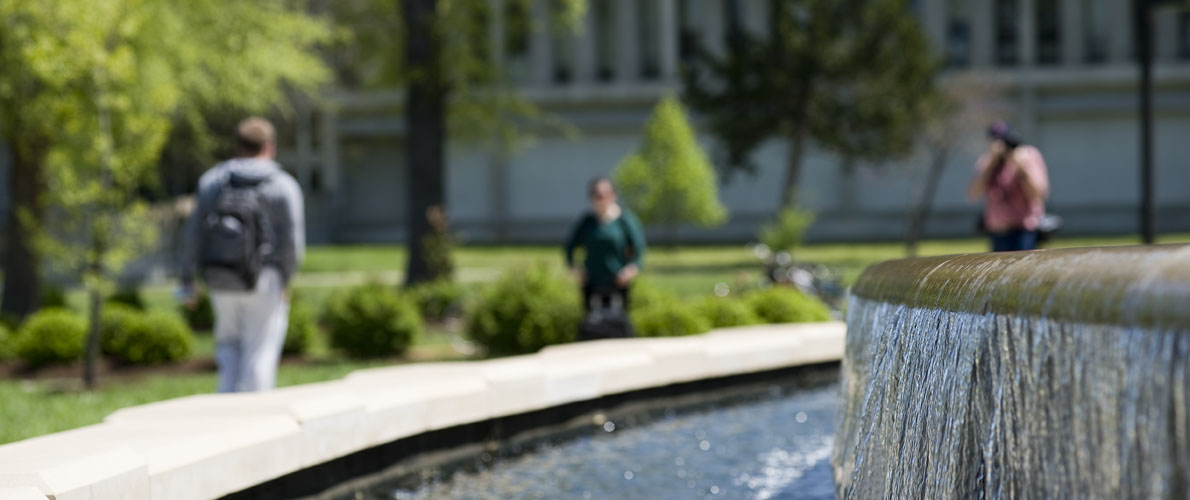 Students walking past Morris Library fountain