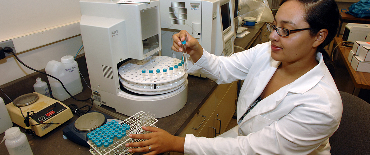 A researcher enters samples into a device. 