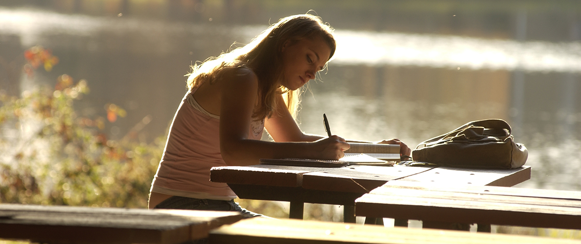 student doing homework near SIU campus lake